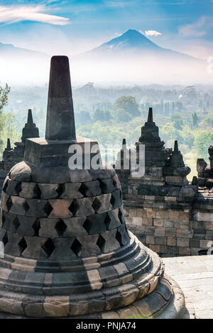 Buddha Statue mit Mount Merapi im Hintergrund, Candi Borobudur buddhistischen Tempel, Muntilan, Java, Indonesien Stockfoto