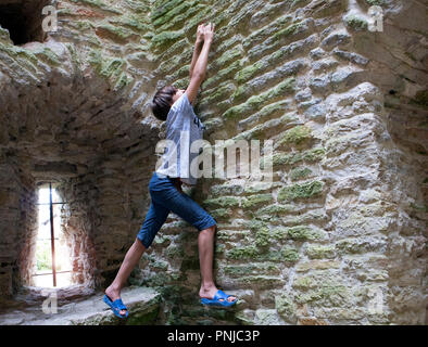 Jungen versuchen, alte Steinmauer im alten Turm zu besteigen Stockfoto