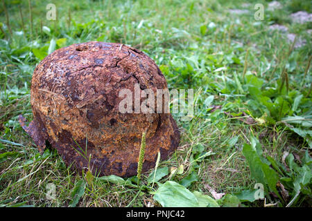 Alten rostigen deutschen Helm des Zweiten Weltkrieges mit Löchern und Rissen, die auf dem Gras Stockfoto