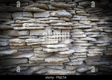 Alten zerfallenden Festung Wand aus weißen flachen hervorstehende Kalksteine, Hintergrund mit dunklen Vignette Stockfoto