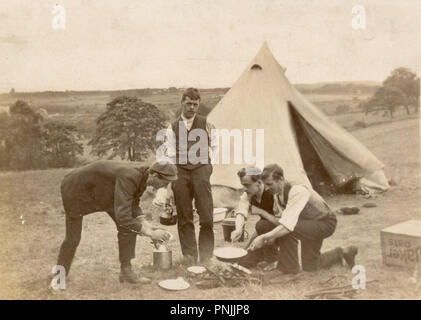 Edwardianische Postkarte von jungen Männern, die auf dem Land campen, Kochen auf offenem Feuer außerhalb Zeltdach, um 1905, Großbritannien Stockfoto