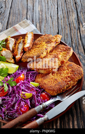 Lecker gebratenes Schweinefleisch Nuggets mit frischem Salat Kalk und Petersilie, auf einem Ton Teller serviert auf einem karierten Serviette, vertikal Stockfoto