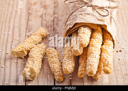 Brot sticks Grissini mit Sesam in craft Pack auf rustikalen Holzmöbeln Hintergrund Stockfoto