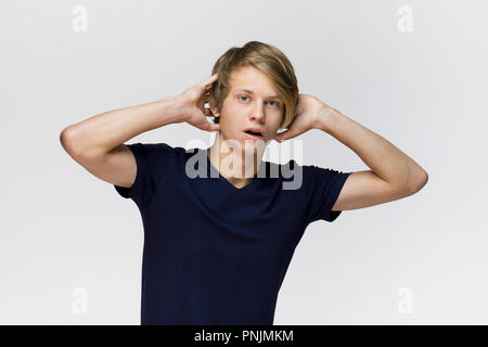 Junger Mann mit schwarzen T-Shirt mit überraschten Gesichtsausdruck vor weißem Hintergrund Stockfoto