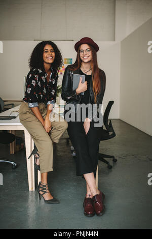 Happy Geschäftsfrauen Sitzung am Rande der Konferenz Tabelle im Büro. Kreative Geschäftsfrau in Hut und Brille mit einem Tablet-PC sitzen mit h Stockfoto