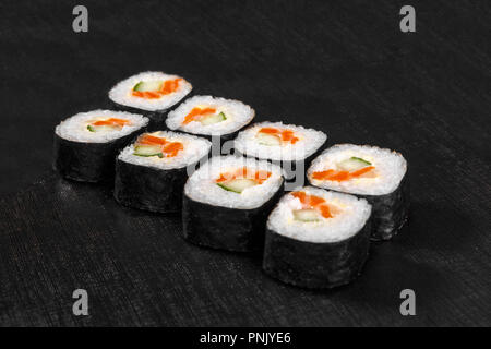 Sushi, Brötchen, hosomaki, mit Lachs, Avocado, Gurke und Philadelphia Käse, rohe Meeresfrüchte, Sojasauce, Ingwer und Wasabi, schwarz isoliert Ba Stockfoto