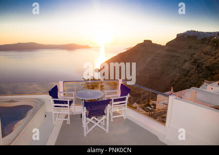 Mit Blick auf die Terrasse mit Tisch und Stühlen an der berühmten Sonnenuntergang auf Santorini, Griechenland, Stockfoto