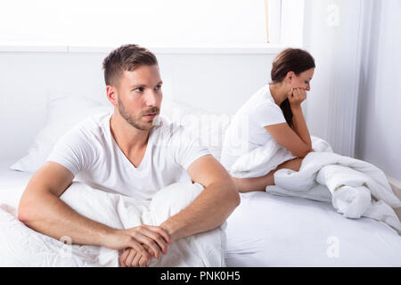 Unglückliche Junge Paare sitzen auf dem Bett im Schlafzimmer Stockfoto