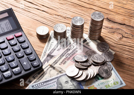Erhöhten Blick auf Rechner mit Stapel von Münzen auf hölzernen Tisch Stockfoto