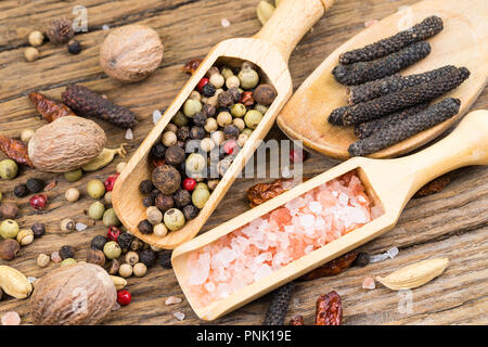 Nahaufnahme der Spice-Schaufeln und einem hölzernen Kochlöffel mit verschiedenen exotischen Gewürzen und weitere Gewürze im Hintergrund auf einem rustikalen, mit Holz Hintergrund Stockfoto