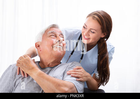 Portrait eines glücklichen Frau Krankenschwester an den älteren Mann suchen Stockfoto