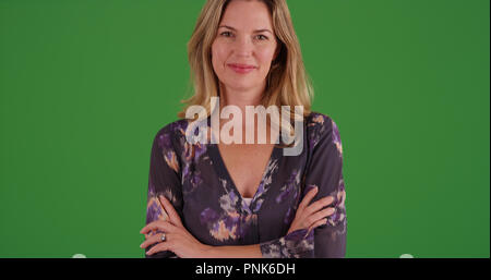 Charmante weiße Frau in ihrem 40s tragen Bluse an der Kamera auf der Suche nach Green Screen Stockfoto