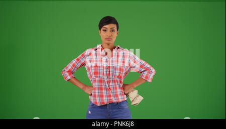 Schwarze Frau Gärtner in Plaid Shirt mit den Händen an den Hüften auf Green Screen Stockfoto