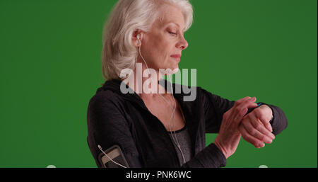 Gesunde alte Frau Einstellen des Timers zu beobachten, bevor Sie Jog on Green Screen Stockfoto