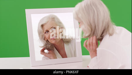 Schön die alten kaukasische Frau Reflexion im Spiegel auf der Green Screen Stockfoto