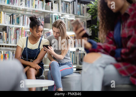 High School Kursteilnehmer auf Smartphones in der Bibliothek Stockfoto