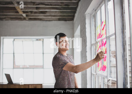 Jungen Erwachsenen männlichen Brainstorming in einer creative Office mit Haftnotizen Stockfoto