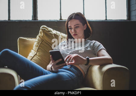 Tausendjährige Sie Ihr Smartphone in ein Loft Stockfoto