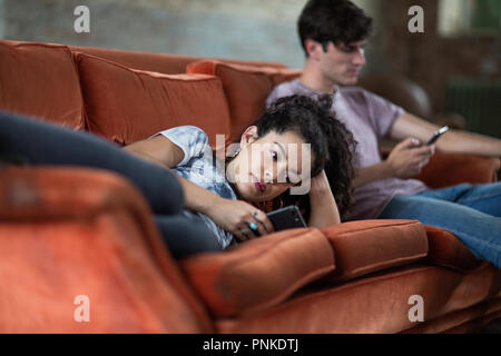 Millennials mit Smartphones entspannen auf dem Sofa Stockfoto