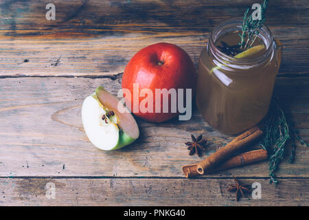 Apple Cider (Apfelwein) oder Glühwein Chai mit Zimtstangen und frische Äpfel auf Holz- Hintergrund. Herbst Getränke. Winter Stimmung. Kopieren Sie Platz. Stockfoto