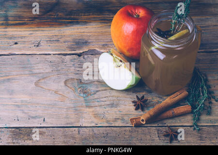 Apple Cider (Apfelwein) oder Glühwein Chai mit Zimtstangen und frische Äpfel auf Holz- Hintergrund. Herbst Getränke. Winter Stimmung. Kopieren Sie Platz. Stockfoto