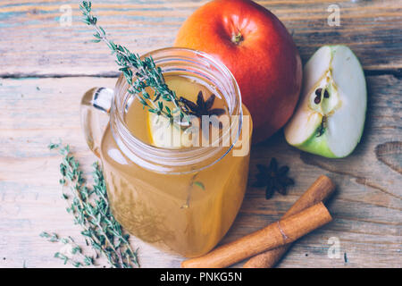 Apple Cider (Apfelwein) oder Glühwein Chai mit Zimtstangen und frische Äpfel auf Holz- Hintergrund. Herbst Getränke. Winter Stimmung. Stockfoto