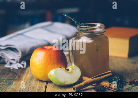 Apple Cider (Apfelwein) oder Glühwein Chai mit Zimtstangen und frische Äpfel auf Holz- Hintergrund. Herbst Getränke. Winter Stimmung. Stockfoto