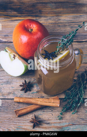 Apple Cider (Apfelwein) oder Glühwein Chai mit Zimtstangen und frische Äpfel auf Holz- Hintergrund. Herbst Getränke. Winter Stimmung. Stockfoto