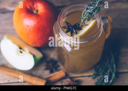 Apple Cider (Apfelwein) oder Glühwein Chai mit Zimtstangen und frische Äpfel auf Holz- Hintergrund. Herbst Getränke. Winter Stimmung. Stockfoto