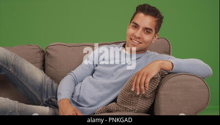 Portrait von hübscher junger spanischer Mann auf der Couch entspannen auf der grünen Bildschirm Stockfoto