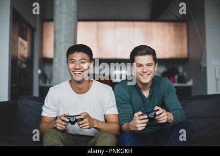 Männliche Freunde spielen auf einer Spielekonsole Stockfoto