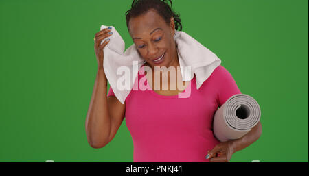 Alte schwarze Frau selbst Abwischen mit einem Handtuch nach Pilates Workout auf Green Screen Stockfoto