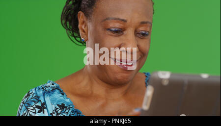 Nahaufnahme der alte schwarze Frau mit tablet device auf Green Screen Stockfoto