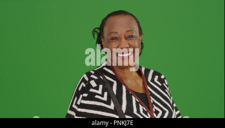 Gerne ältere schwarze Frau posiert für ein Portrait auf der grünen Bildschirm Stockfoto