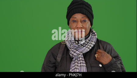 Eine ältere schwarze Frau in warme Winterkleidung auf Green Screen Stockfoto