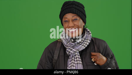 Eine ältere schwarze Frau tragen Winter Kleidung Lächeln auf Green Screen Stockfoto