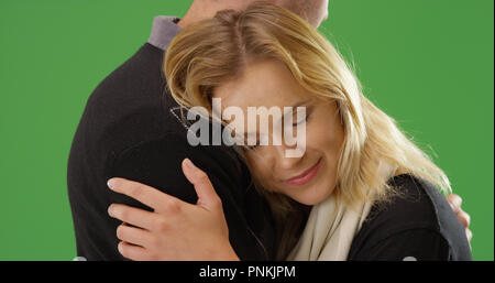 Nahaufnahme der jungen weißen Freundin umarmte ihren Freund auf Green Screen Stockfoto