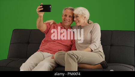 Cute senior Paar ein selfie mit Smartphone zu Hause am Bildschirm grün Stockfoto