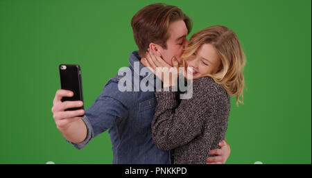 Mann küssen Freundin nach Engagement während der Einnahme von selfie auf Green Screen Stockfoto