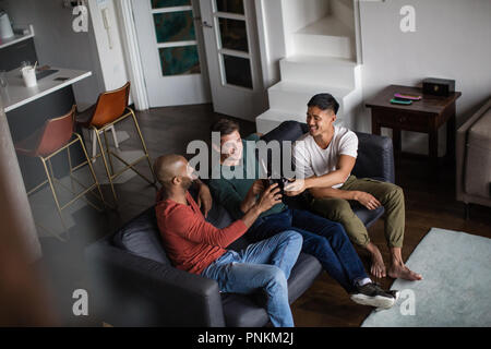 Männliche Freunde mit einem Bier zusammen in einer Wohnung Stockfoto