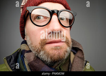 Close up Portrait von europeam Mann mittleren Alters in den lustigen warme Mütze und Brille bemerken versteckte Kamera. Jemand ist Spionage nach mir wirklich. Stockfoto
