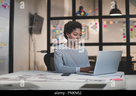 Afrikanische amerikanische weibliche Arbeit spät in einem Büro Stockfoto