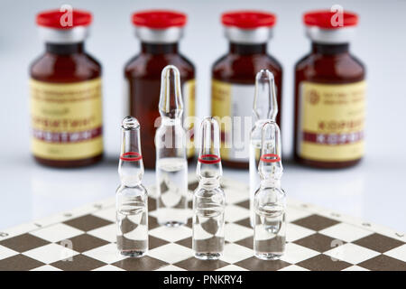 Ampullen auf Schachbrett, Flaschen mit Medizin. Stockfoto