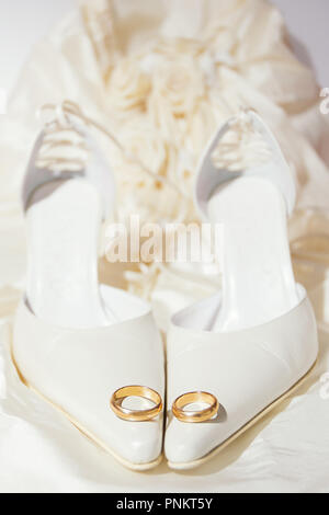 Trauringe und Damenschuhe mit einem Kleid auf dem Hintergrund Stockfoto