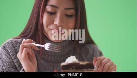 Gerne asiatische Frau Kuchen essen auf der grünen Bildschirm Stockfoto