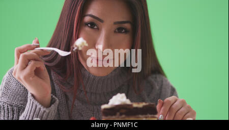 Gerne asiatische Frau Kuchen essen auf der grünen Bildschirm Stockfoto