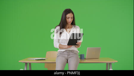 Ein Hispanic Büro arbeitet sie an ihrem Tablet auf Green Screen Stockfoto