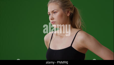 Tausendjährige weißes Mädchen in der Turnhalle Kleidung Blick in die Ferne auf Green Screen Stockfoto