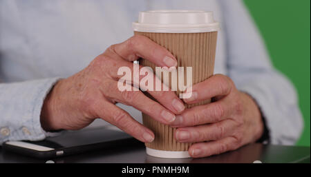 In der Nähe der alten Frau, die Hände, die Tasse Kaffee auf grünen Bildschirm Stockfoto