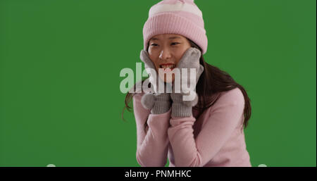 Junge asiatische Frau glücklich im Winter Kleidung selbst Erwärmung auf die Green Screen Stockfoto